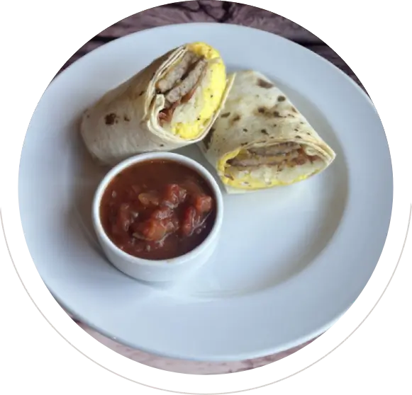 Breakfast burrito cut in half with salsa on a white plate.